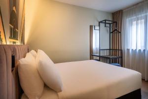 una camera con un letto bianco e una finestra di Hotel Hubert Grand Place a Bruxelles