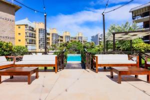 une terrasse avec bancs en bois et une piscine dans l'établissement Victoria Village, à Carilo