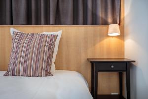 een bed met een kussen en een nachtkastje met een lamp bij Hotel Bla Bla in Brugge