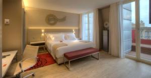 a hotel room with a bed and a desk and a window at NH Collection Porto Batalha in Porto