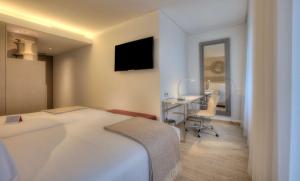 a bedroom with a bed and a desk and a television at NH Collection Porto Batalha in Porto