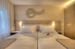 a bedroom with a large white bed with a clock on the wall at NH Collection Porto Batalha in Porto