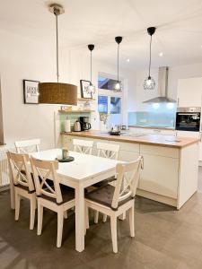 cocina blanca con mesa blanca y sillas en Ferienwohnung Sauke, en Uelzen