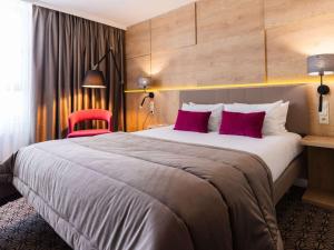 a hotel room with a large bed and a red chair at Mercure Lublin Centrum in Lublin