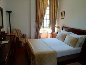 a bedroom with a bed and a chair and a window at Turim Club Azeitao Hotel in Setúbal