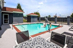 uma piscina com uma mesa e cadeiras num pátio em Days Inn by Wyndham Baton Rouge I-10 em Baton Rouge