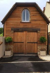 une maison avec un garage en bois avec deux plantes dans l'établissement Quaint Studio Loft Room nr Hampton Court, à Thames Ditton