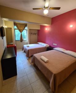 1 dormitorio con 2 camas y pared roja en Hotel Arcadia Cuernavaca, en Cuernavaca