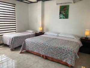 two beds in a room with two lamps on tables at Galapagos Dreams in Puerto Ayora