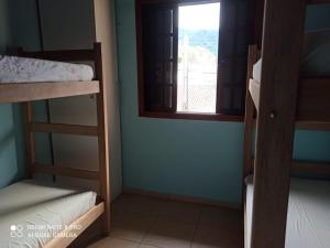 Zimmer mit 3 Etagenbetten und einem Fenster in der Unterkunft Litoral Norte Pousada in Caraguatatuba