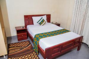 um pequeno quarto com uma cama e um banco em Kenendia Hotel em Kampala