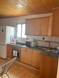 cocina con armarios de madera y nevera blanca en Garza Attic House, en Ojos de Garza