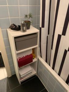 un pequeño estante blanco en el baño con ducha en Your cosy private Apartment, en Múnich