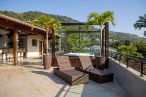 een patio met palmbomen en een tafel en stoelen bij Inn House Angra in Angra dos Reis