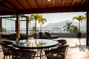 een patio met een glazen tafel en stoelen bij Inn House Angra in Angra dos Reis