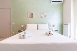 a bedroom with a large white bed with towels on it at Hostly- Don Bosco Light Lodge in Rome