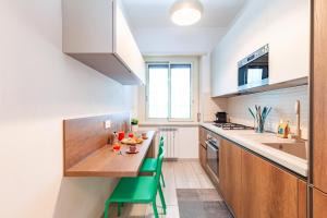 a kitchen with a wooden table and green chairs at Hostly- Don Bosco Light Lodge in Rome