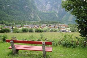 un banc rouge assis dans un champ avec un village dans l'établissement Holiday Homes Obertraun/Oberösterreich 86, à Obertraun