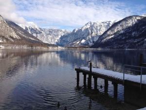 un quai au milieu d'un lac avec des montagnes enneigées dans l'établissement Holiday Homes Obertraun/Oberösterreich 86, à Obertraun