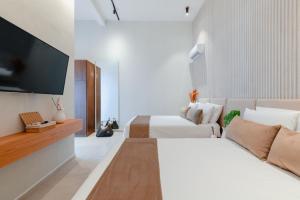 a hotel room with two beds and a flat screen tv at Areia Boutique Hotel - Puerto Morelos in Puerto Morelos