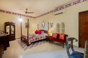 - une chambre avec un lit et une chaise dans l'établissement Dera Rawatsar - Heritage Hotel, à Jaipur