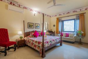 - une chambre avec un lit et une chaise rouge dans l'établissement Dera Rawatsar - Heritage Hotel, à Jaipur