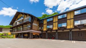 een geel en zwart gebouw met een parkeerplaats bij Mogamitakayu Zenshichinoyu Ohira in Zao Onsen