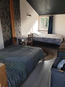 1 dormitorio con 2 camas, mesa y ventana en L'escale du lac, en Saint-Julien-des-Landes