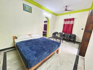 ein Schlafzimmer mit einem Bett und Stühlen in der Unterkunft The Kaya group stay Srirangam in Srīrangam