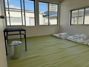 ein leeres Zimmer mit einem Tisch und einigen Fenstern in der Unterkunft Wholeearth Ryokan Hiroshima in Hiroshima