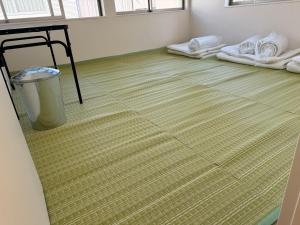 Zimmer mit Teppichboden und Mülleimer in der Unterkunft Wholeearth Ryokan Hiroshima in Hiroshima