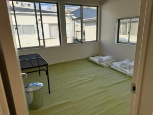 ein leeres Zimmer mit zwei Fenstern und einem Tisch in der Unterkunft Wholeearth Ryokan Hiroshima in Hiroshima