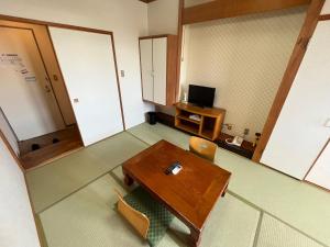 een kamer met een tafel en een tv. bij Hotel Marsh Land in Kushiro