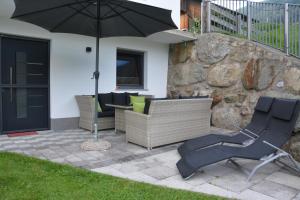 une terrasse avec une table, des chaises et un parasol dans l'établissement Appartement Wieshof, à Neukirchen am Großvenediger