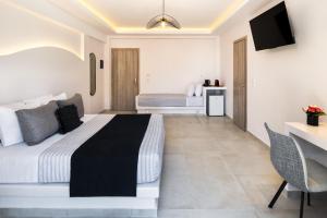 una camera con letto, scrivania e TV di Santorinn Suites Fira a Firà