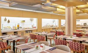 un ristorante con tavoli, sedie e bancone di NH Collection Barcelona Podium a Barcellona