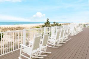 uma fila de cadeiras brancas sentadas num passeio marítimo de madeira gmaxwell gmaxwell gmaxwell em Hilton Garden Inn Ocean City Oceanfront em Ocean City