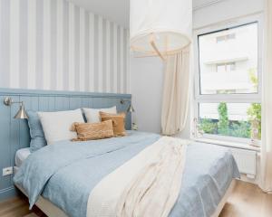 a bedroom with a blue and white bed and a window at Apartament Aqua Przystań 80 - Rumia Novum in Rumia