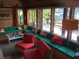 ein Wohnzimmer mit einem grünen Sofa und Fenstern in der Unterkunft alleinstehendes Ferienhaus in Grindelwald