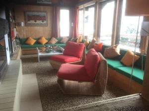 ein Wohnzimmer mit einem Sofa, Stühlen und Fenstern in der Unterkunft alleinstehendes Ferienhaus in Grindelwald