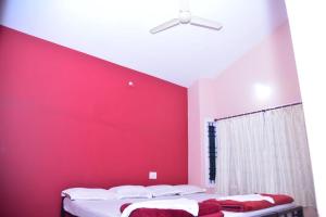 a bedroom with a red wall and two beds at Rock peak view homestay in Avathi