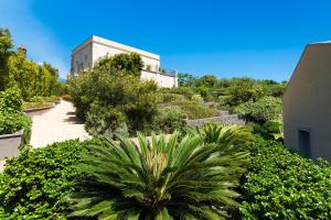 un jardín con una palmera y un edificio en Kepos Etna Relais & Exclusive Spa, en Santa Venerina