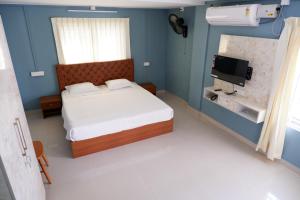 um pequeno quarto com uma cama e uma televisão em Haya Residency em Alappuzha