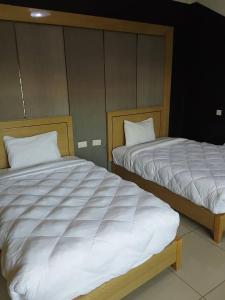 two beds sitting next to each other in a room at Mpatsa Quest Hotels in Lilongwe