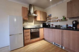 una cucina con frigorifero bianco e armadietti in legno di 2 bedroom apartment a Liverpool