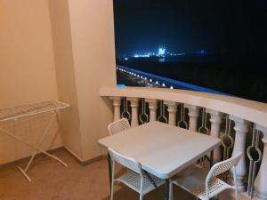 Four Stars Hostel RAS Al-Khaimah في رأس الخيمة: طاولة بيضاء وكراسي على شرفة في الليل