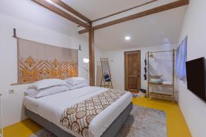 een slaapkamer met een groot bed en een televisie bij Yukke Tembi Homestay in Yogyakarta