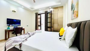 een slaapkamer met een bed, een bureau en een televisie bij Olive Service Apartments - Green Park in New Delhi