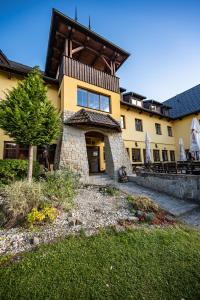 een groot geel gebouw met een boom ervoor bij Valašský Hotel a Pivní lázně OGAR in Luhačovice