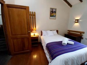 1 dormitorio con 1 cama y puerta de madera en Maison Fortaleza, en Cusco